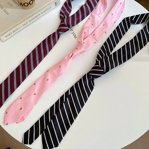 Close-up of JK style striped and heart patterned ties on a white table with accessories