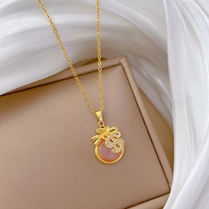 Close-up of golden money bag pendant with pink gemstone and sparkling dollar sign detail