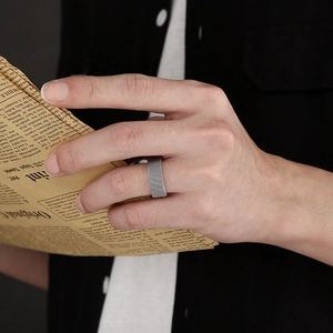 Detailed view of silver mesh stainless steel wide ring worn against a vintage newspaper