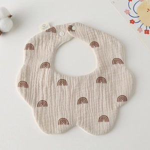 Detail of petal-shaped cotton baby bib with rainbow pattern and snap buttons