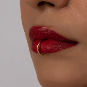 Anello al naso dorato stile hip-hop per uomo e donna, indossato da una modella su sfondo grigio