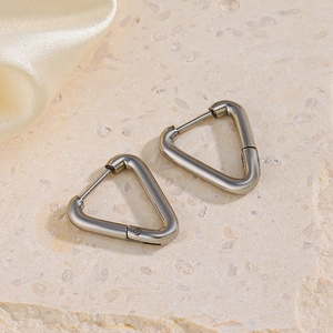 Minimalist silver triangle earrings on stone surface with silk fabric background
