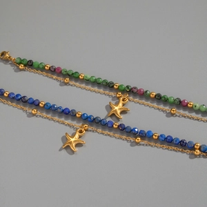 Dettaglio di bracciale multistrato con pietre naturali, catena dorata e ciondolo a stella
