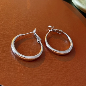 Vue détaillée de boucles d'oreilles créoles géométriques polies en argent sur cuir sombre