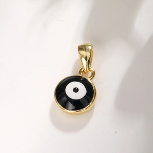 Macro view of gold-plated round evil eye pendant with black and white enamel detail