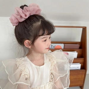 Detail of pink chiffon large scrunchie worn on a high bun for a sweet feminine hairstyle