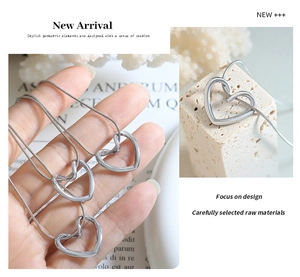 Macro detail of silver hollow heart pendant with sleek circular snake chain