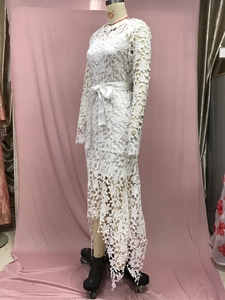 Detailed view of white hollow lace dress with satin waist belt and asymmetrical hem