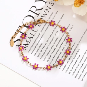 Detailed macro view of golden stainless steel chain with purple enamel daisy floral charms