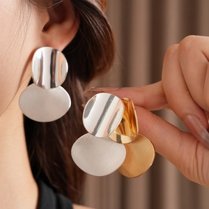 Macro detail of large geometric brushed oval drop earrings in gold and silver finish