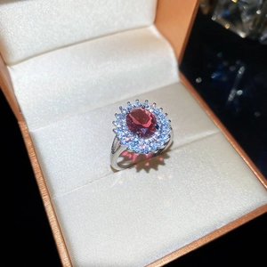 Gros plan d'une bague en argent avec pierre rouge ovale et zircons dans son coffret