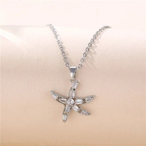Sparkling silver starfish necklace with zircon stones on a soft peach background