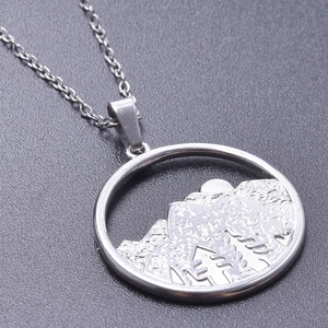 Detail of silver round mountain pendant with hollowed-out tree and sun engraving