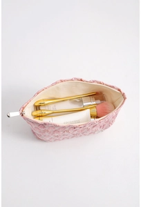 Inside view of pink embossed makeup bag showing storage space for brushes and skincare