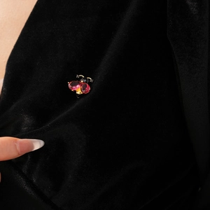 Detailed close-up of a vintage bee brooch with red teardrop stones on black fabric
