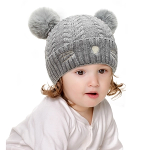 Detail of grey knitted baby hat with soft faux fur pom-poms and cute cat face embroidery