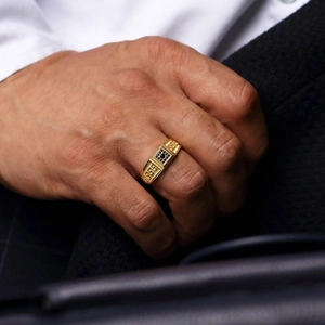 Gold mens ring with nine black stones and Greek pattern engraving on dark suit background