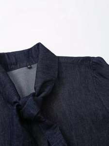 Détail du col d'une chemise en jean bleu foncé avec nœud et étiquette de taille M