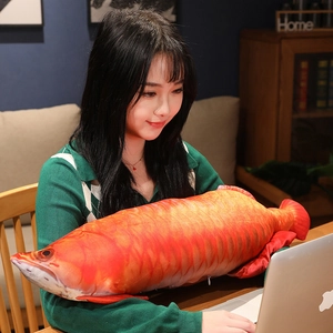 Detailed view of large plush golden arowana pillow being held by a model in a cozy home setting