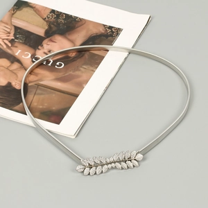 Detail shot of silver elastic metal waist chain with elegant leaf-shaped buckle on a magazine