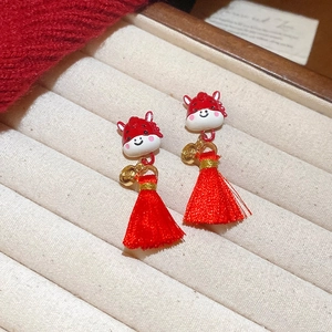 Close-up of Chinese style horse stud earrings with red tassels on jewelry display tray