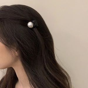 Elegant single white pearl hair clip shown on dark curly hair for a minimalist look