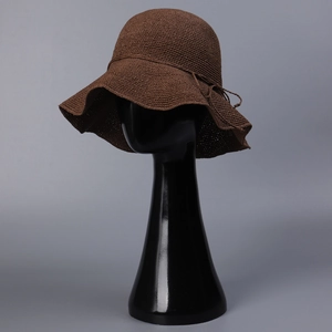 Detailed crochet texture of brown straw sun hat with wavy brim and decorative string tie