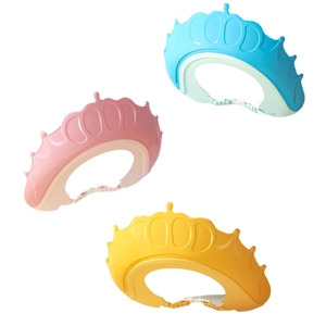 Three crown-shaped waterproof baby shower caps in blue, pink, and yellow silicone