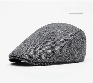 Detail of light gray winter beret showing thick wool texture and metal brand plaque