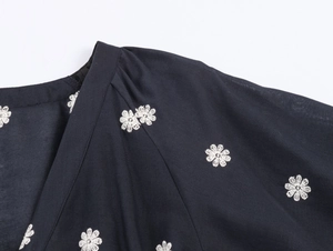 Detail of elegant V-neckline and white floral embroidery on a black puff sleeve dress