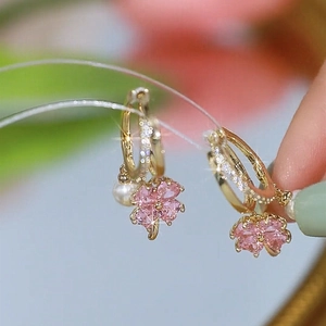 Macro view of gold hoop earrings with pink clover gemstone and white pearl pendant