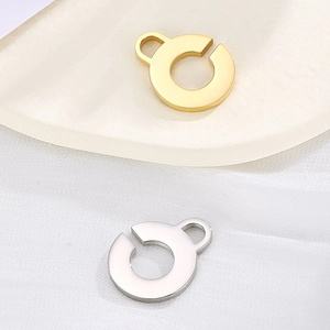 Circular hollow open pendant in gold and silver finish stainless steel on white fabric