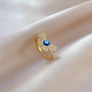 Detail of gold butterfly ring with blue evil eye zircon on champagne silk background