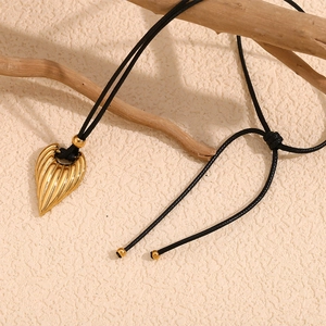 Detail of gold heart pendant with black cord on a rustic textured paper background