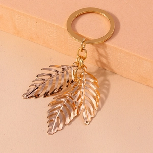 Detail showing golden hollow leaf charms on a metallic keychain with a polished finish