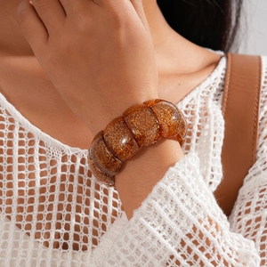 Close-up of amber acrylic chunky bracelet with gold flakes worn on a female wrist