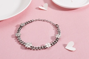 Detail of silver clover bracelet with sparkling rhinestones on a pink textured background