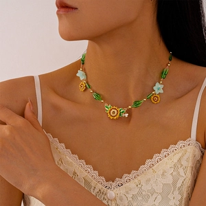 Close-up of beaded necklace with sunflower pendant and green floral charms on model