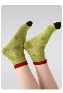 Detail of green mesh kids sock with yellow polka dots and red contrast ribbed cuff