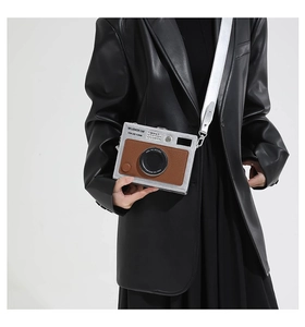 Detail showing vintage camera style crossbody bag with silver strap and metallic finish