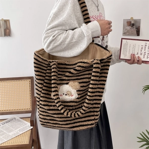 Detail of striped plush tote bag with cute dog patch shown in a cozy indoor setting