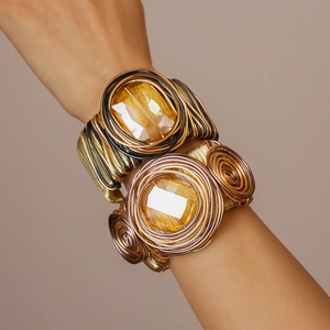 Close-up of bohemian hand-woven wire cuffs with large amber gemstones and gold textures
