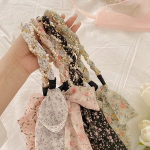 Close-up of floral hairbands with pearl and metal chain braided bow details