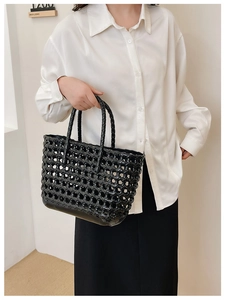 Detail of black woven hollow tote bag with glossy finish for summer beach vacations