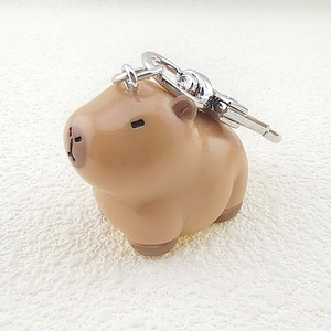 Close-up of a cute 3D resin capybara keychain with a silver metal clasp on a white background