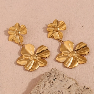Detailed view of 18K gold plated double flower drop earrings on a textured beige background