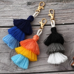 Handmade boho multilayer cotton tassel keychains in three color gradients on wood background