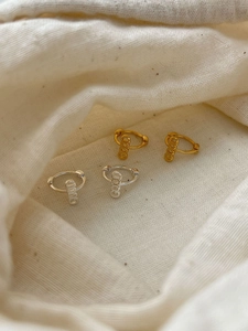 Macro shot of 925 silver mini hoop earrings with vertical GOOD letter pendants