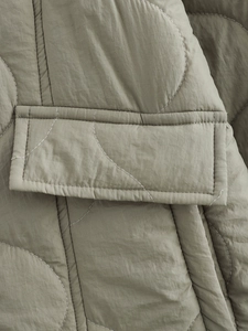 Detail of sage green quilted jacket showing onion stitching and pocket seam texture