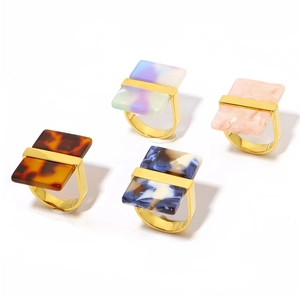 Close-up of four 18k gold U-shaped rings with colorful resin tortoiseshell and marble inserts